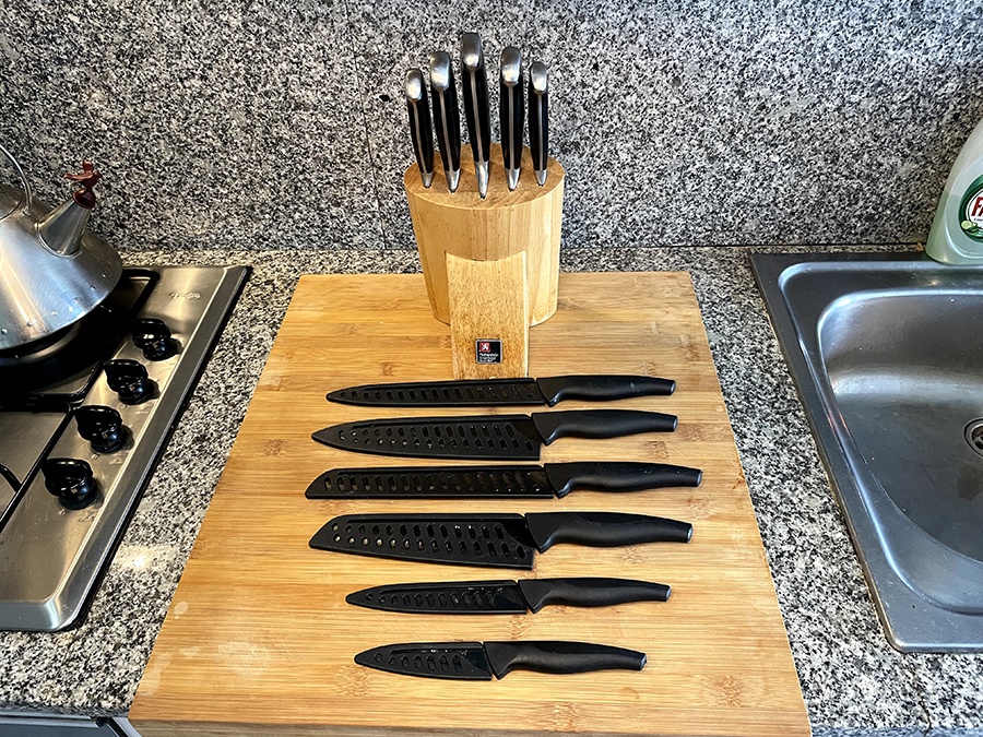 Two different kitchen knife sets on a wooden chopping board